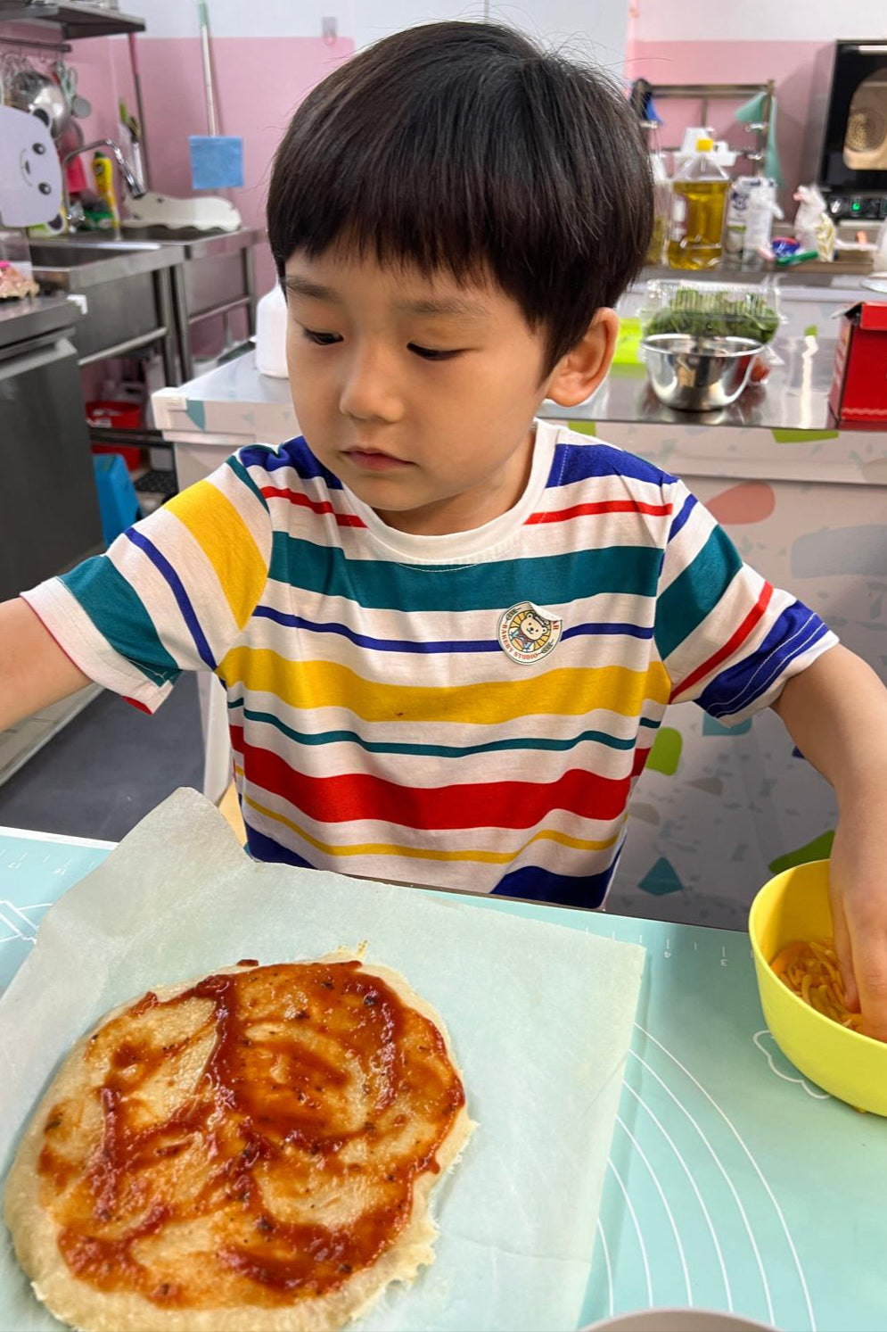 Child in a kitchen with a homemade pizza and bowl of food