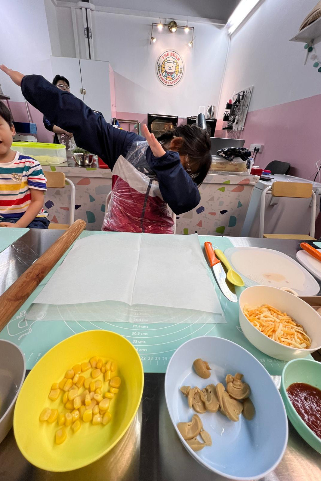 Children playing with food on a table in a kitchen setting