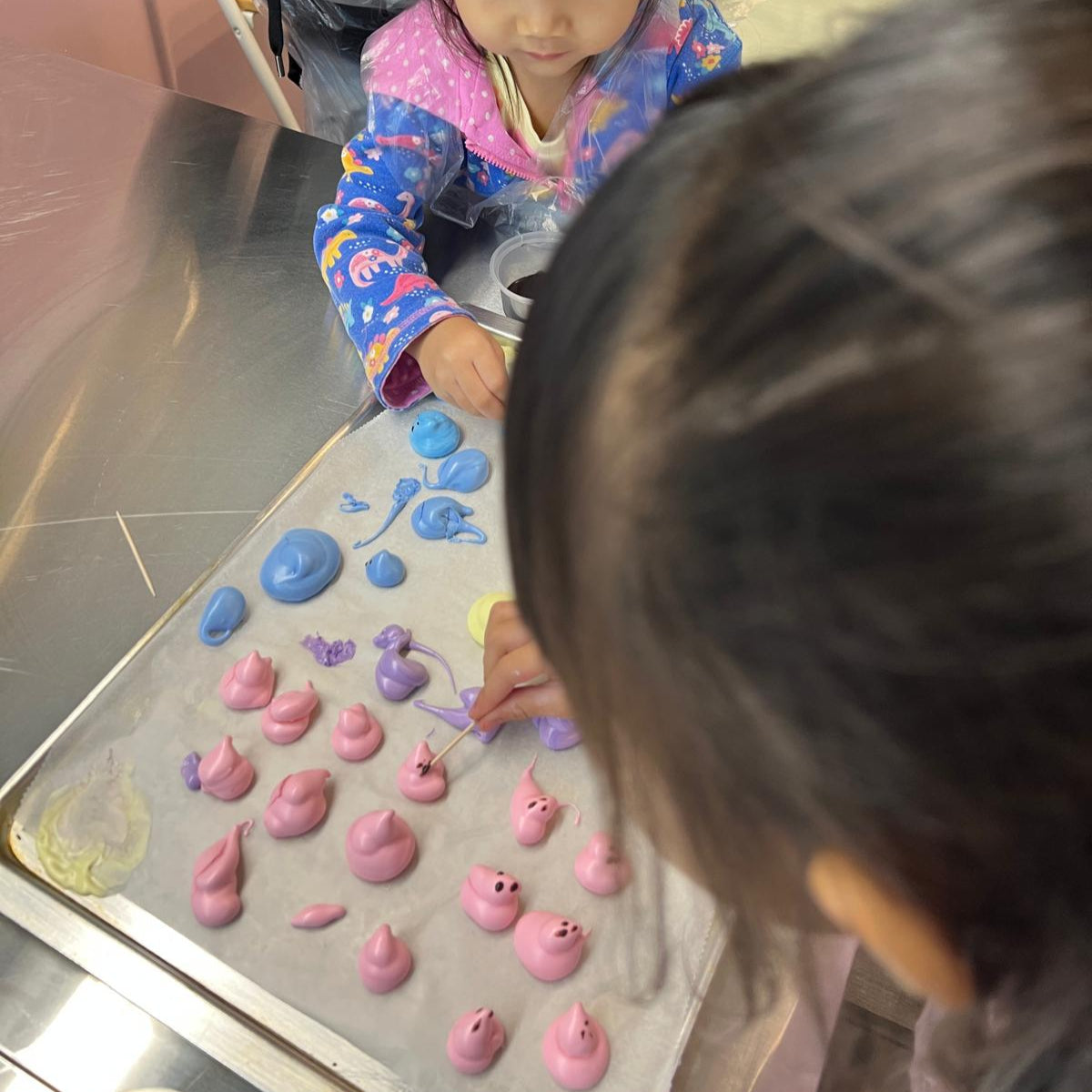 Two children playing with pink and blue toys on a tray.