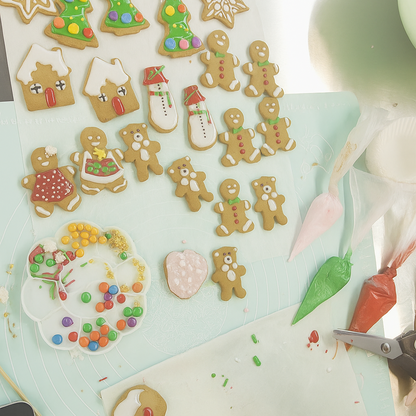 Decorative cookies shaped like gingerbread men and other figures on a cutting board.