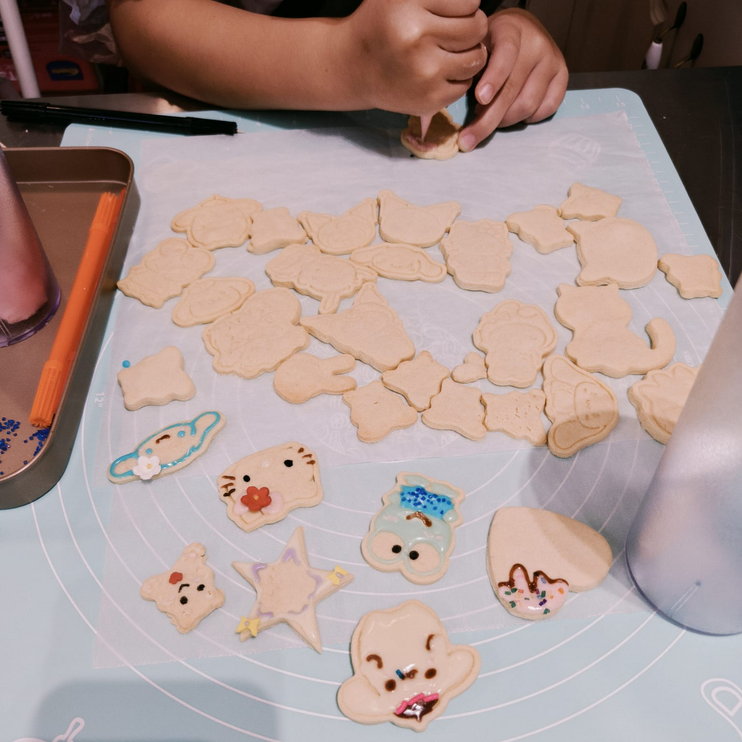 Children's hands shaping cookie dough into animal shapes on a baking mat.
