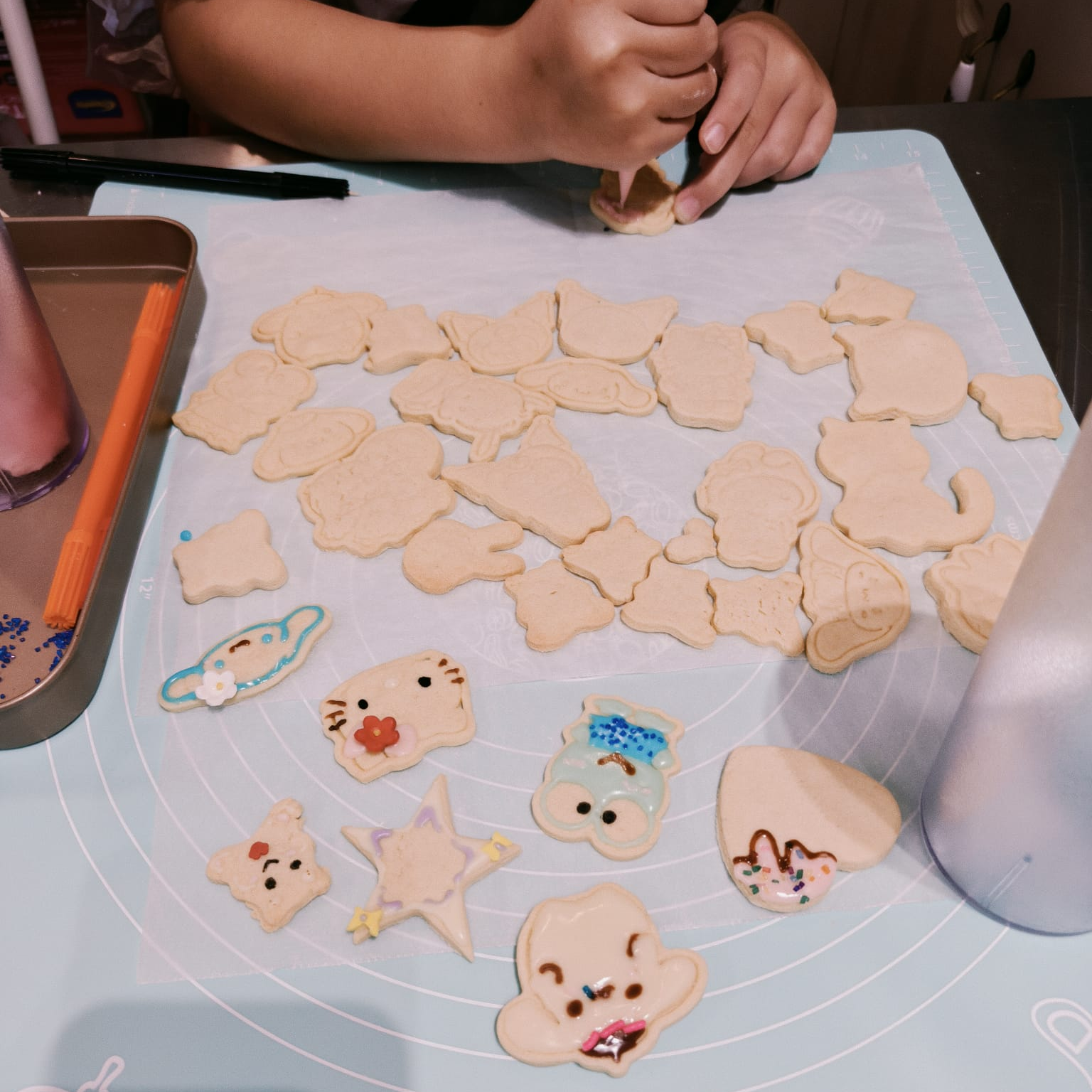 Children's hands shaping cookie dough into animal shapes on a baking mat.