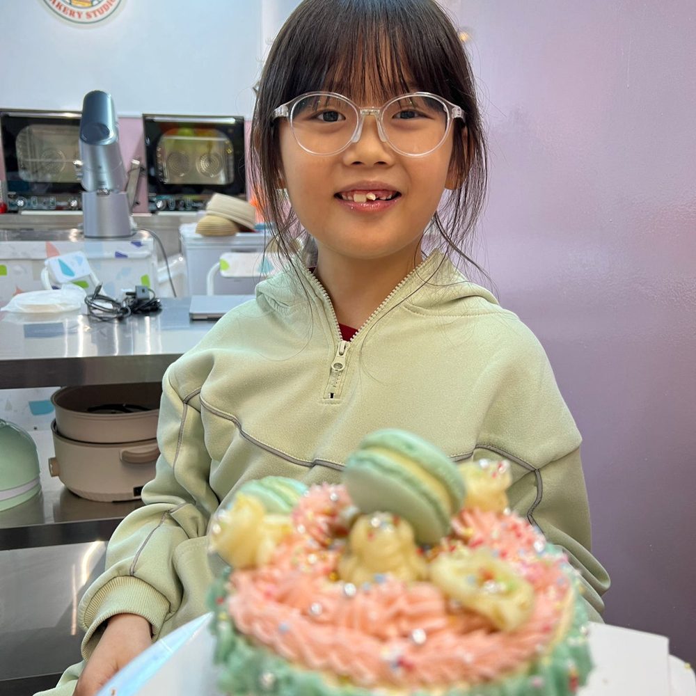 A happy child showing off her decorated cake at Bear Bakery Studio